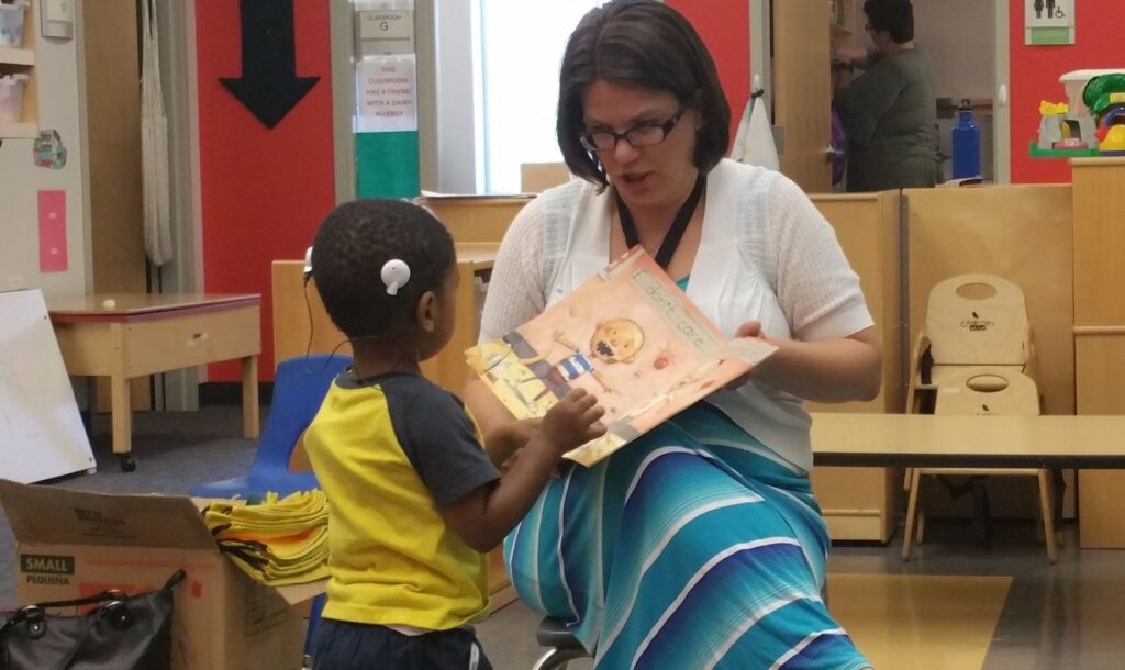 An Anixter team member reading a book to a young boy